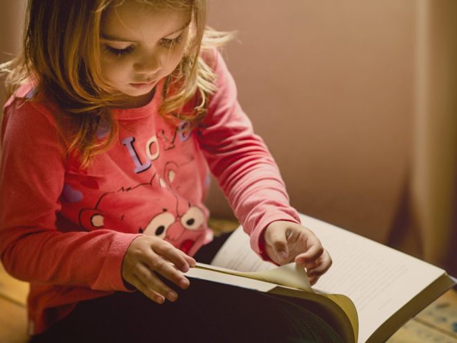 a little girl reading a book about mindfulness activities for kids