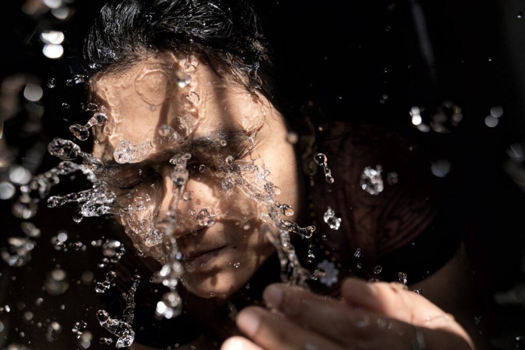 A woman splashes water on her face.
