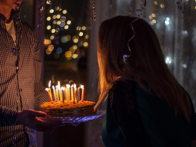 A woman blows out candles on a birthday cake.