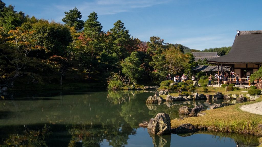 A Japanese-style house sits next to a lake. 