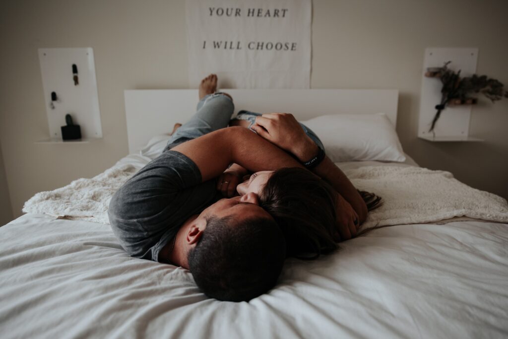 A couple hugs lying down on a bed. 