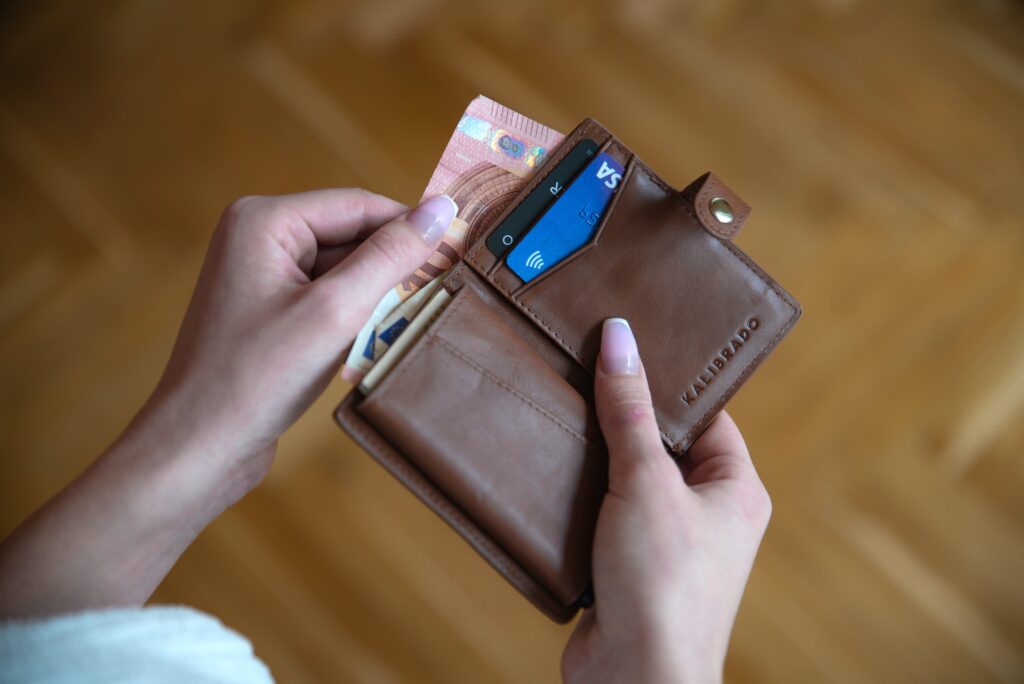 A woman pulls money out of a wallet. 
