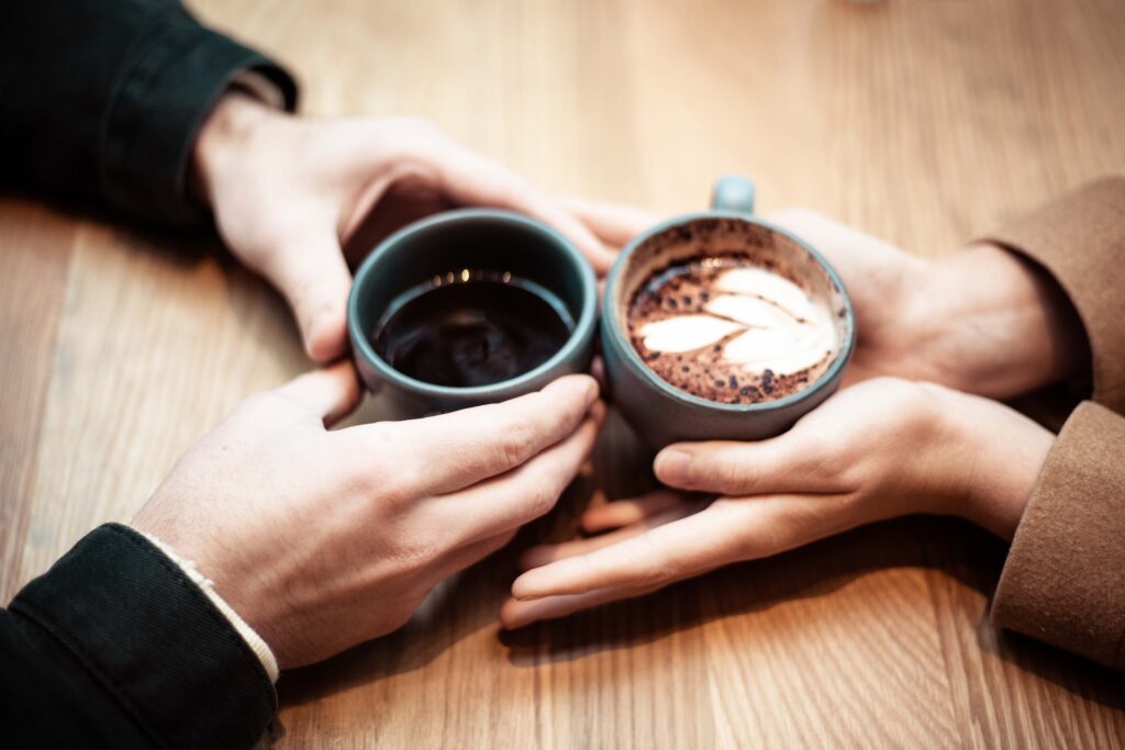 Two people holding coffee mugs on a table.
