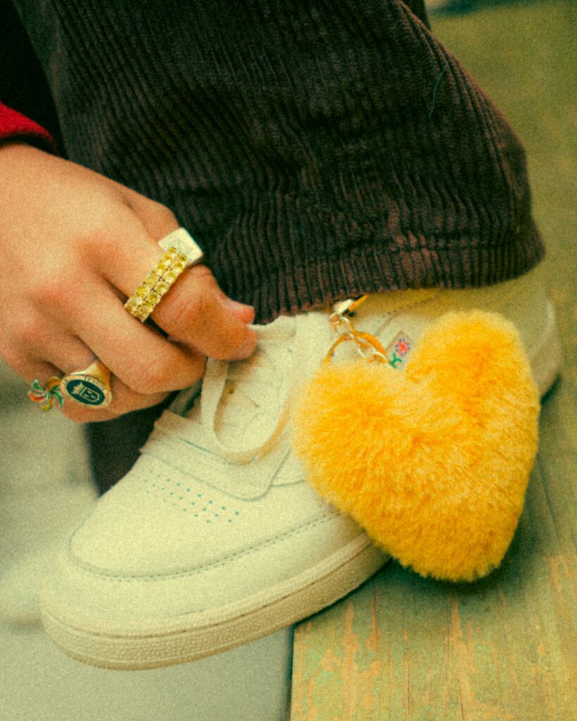 A yellow heart keychain on a white sneaker