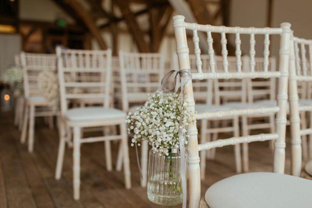 A vase of baby's breath flowers hangs on a chair. 
