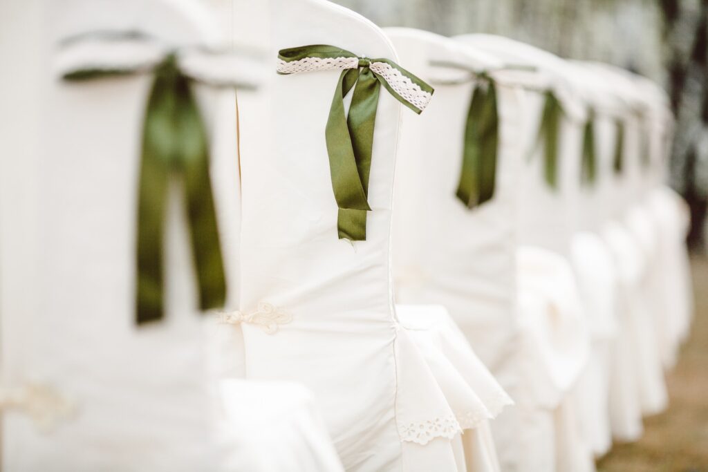 White chairs with green ribbons tied on the corners.