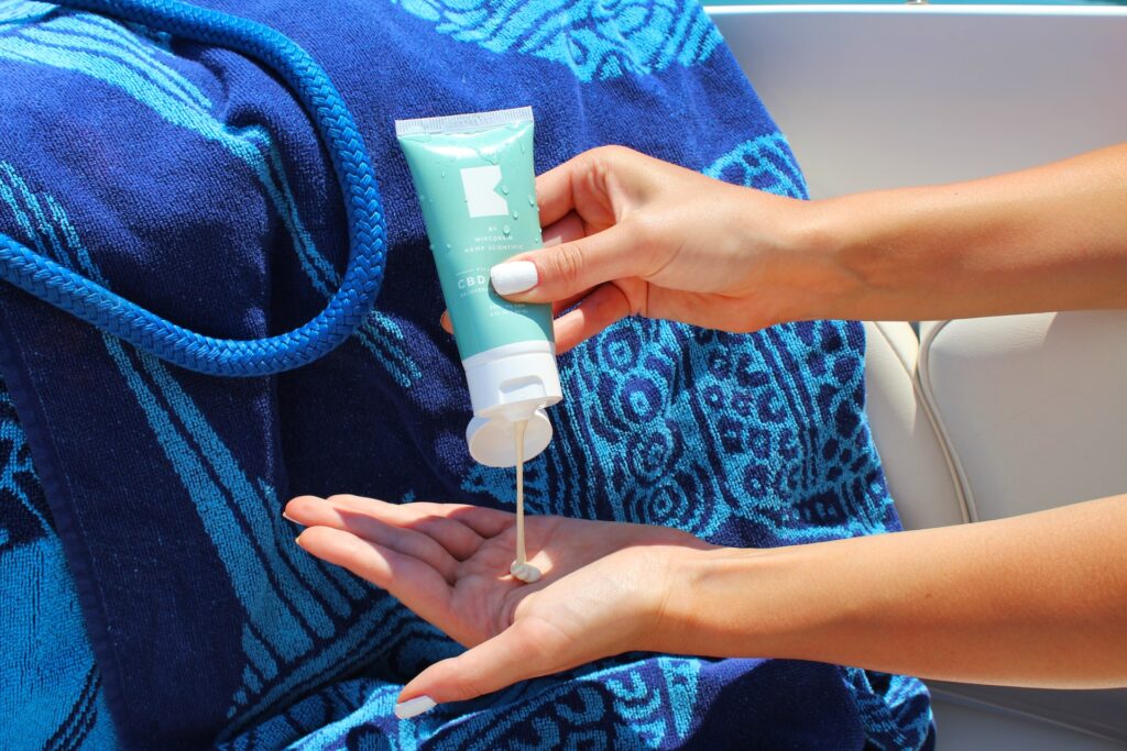 A person squeezes a bottle of sunscreen into their hand.