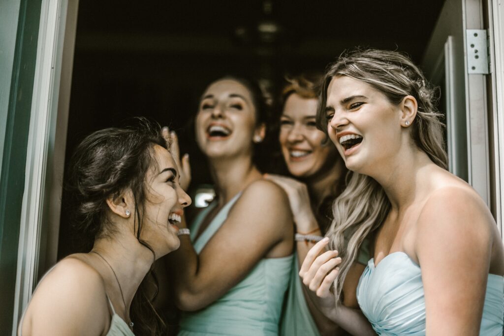 Bridesmaids wearing blue dresses laugh together.