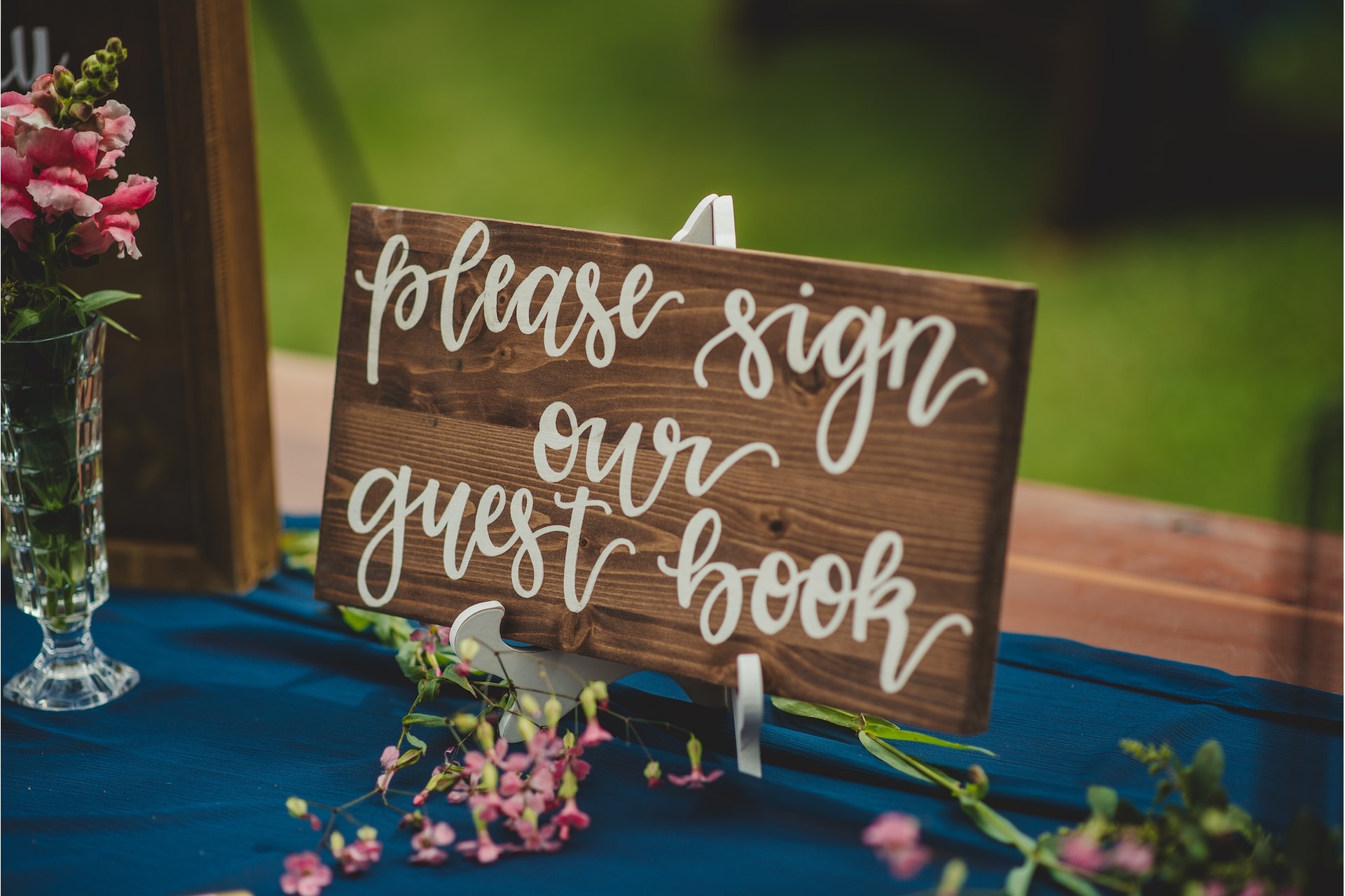 Sign on a table with the words, 'please sing our guest book'