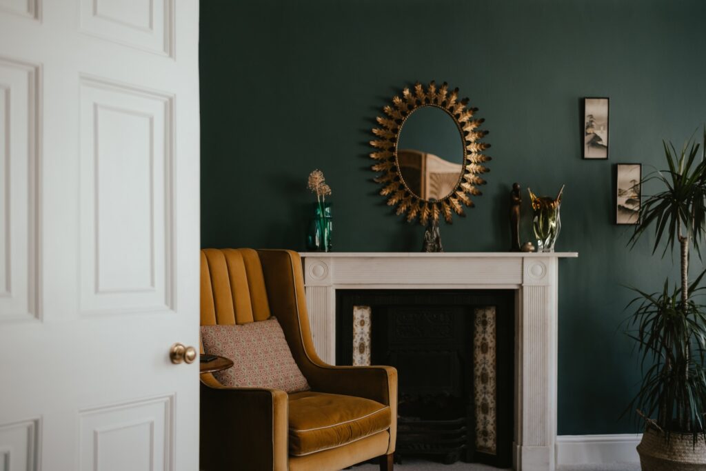 An oval gold mirror hangs over a fireplace. 