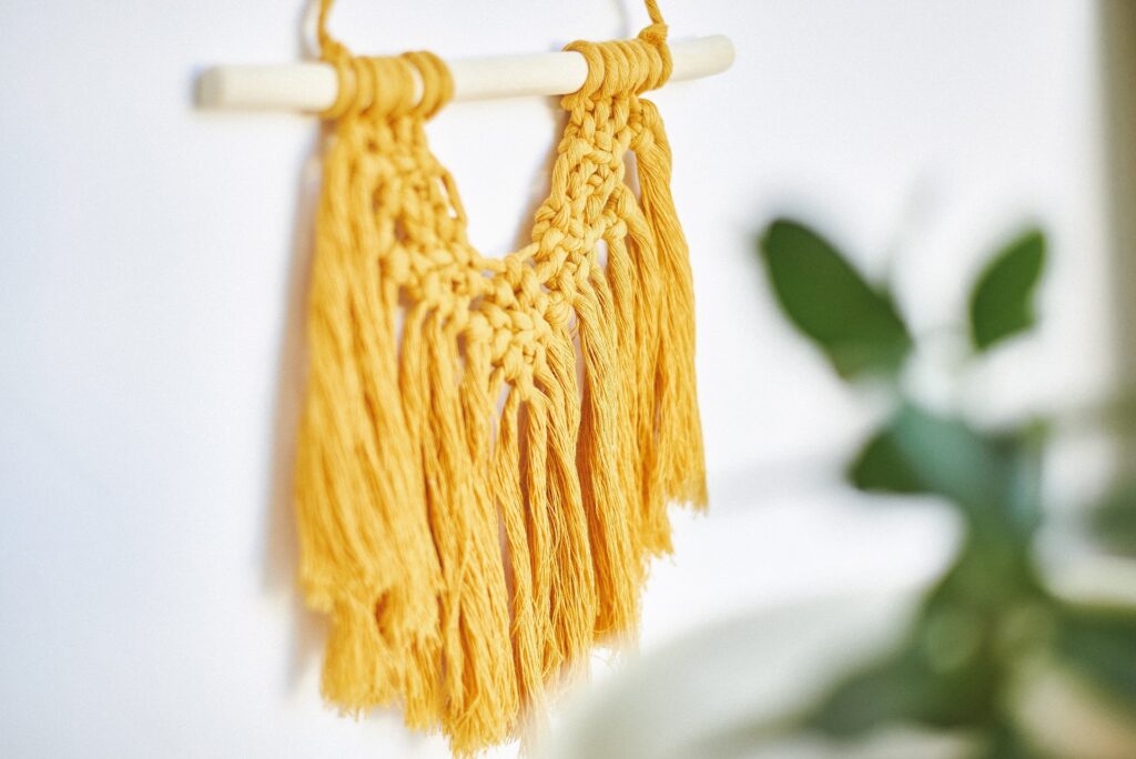 A yellow macrame tapestry hangs on a wall.