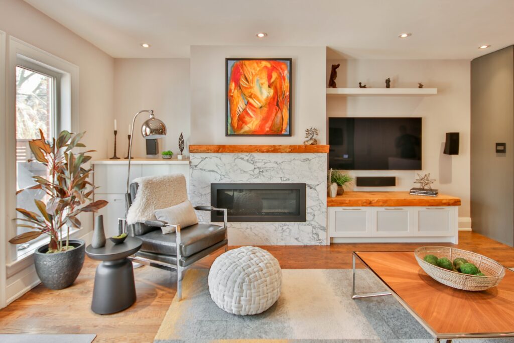 A piece of orange abstract art hangs over a fireplace. 