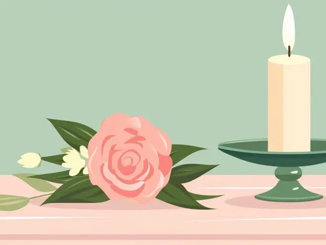 A lit candle on a table next to a flower.