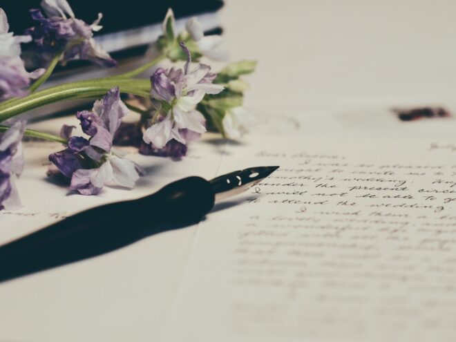 A pen and a wedding message to a couple with cursive writing, accompanied by purple flowers