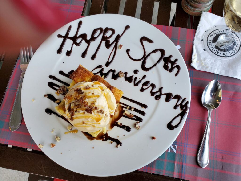 A dessert with chocolate writing on the plate that says "happy anniversary"