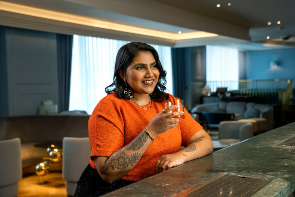 A woman holding a drink at a bar.