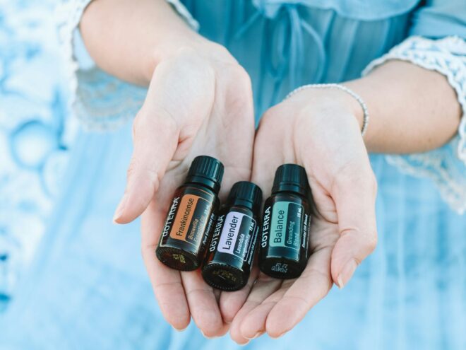 A person in a blue dress with three doTERRA essential oils laying in both hands