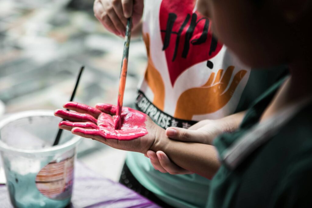 Person painting a child's hand.