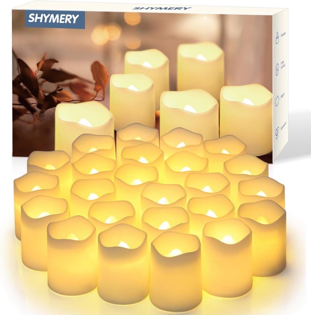 A group of 24 battery powered votive candles sits on a white background in front of the box they come in.