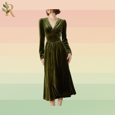 A woman stands in a dark green velvet dress with a corset middle and buttons up the torso. It has a deep V-neck and long sleeves.