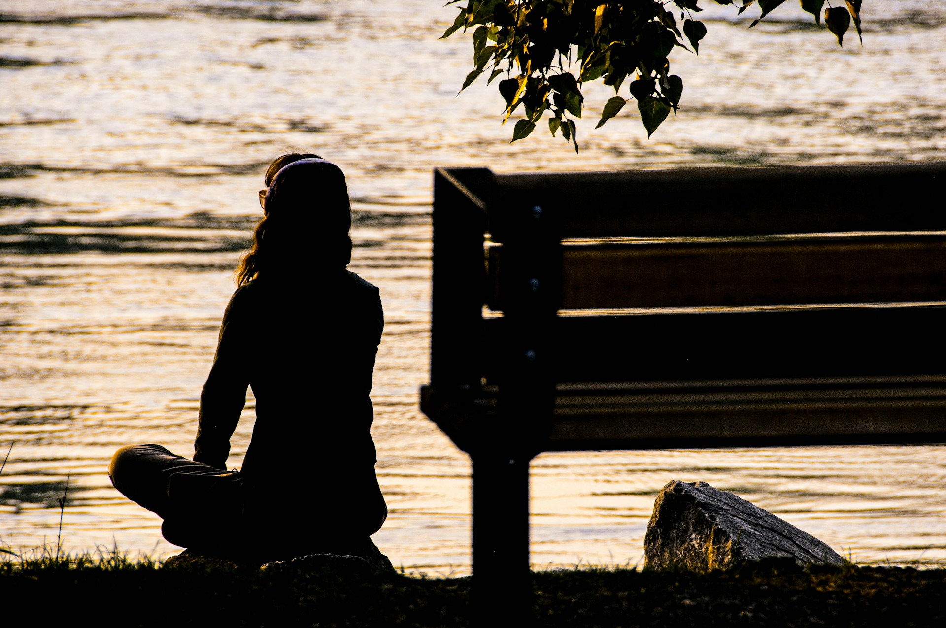 A woman sits and meditates by a river.