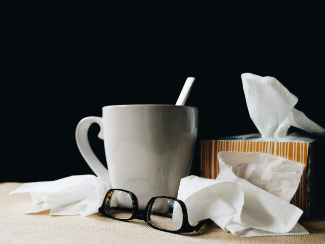 White cup with tissues and a pair of glasses.