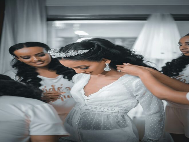 Women dressed in white preparing a person for wedding.