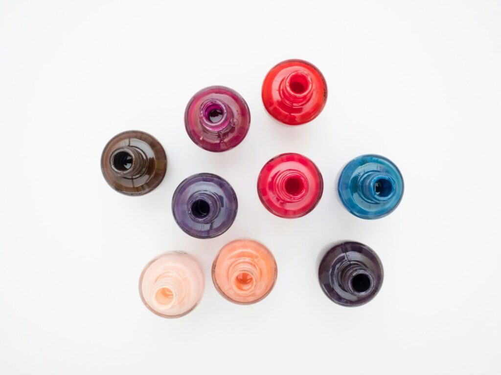 Nine bottles of nail polish in different fall nail colors sit on a white table below the camera.