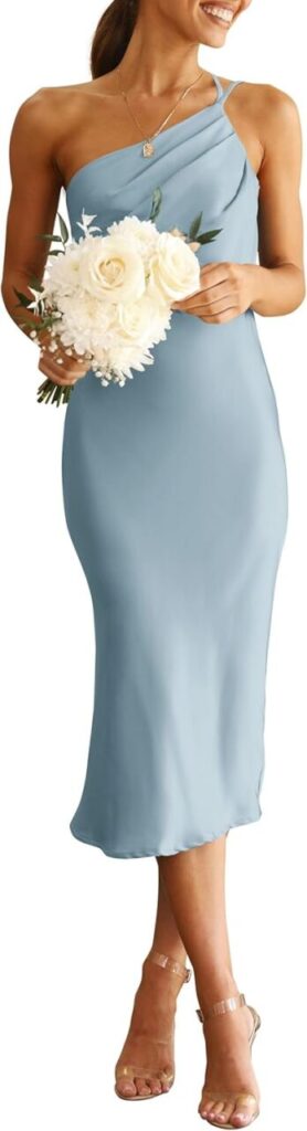 a woman stands in heels and a light blue cocktail dress that's one-shouldered and has pleats by the neckline.