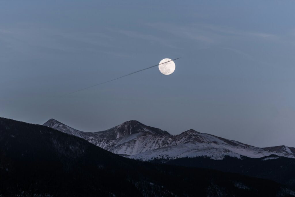 A mountain range with a full moon.