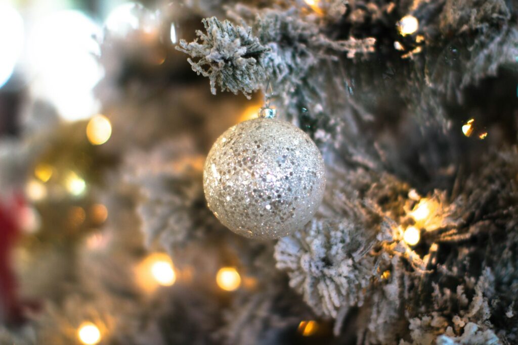 A tree covered in white snow, yellow lights and silver bulbs decorate the inside of a neutral Christmas aesthetic house.