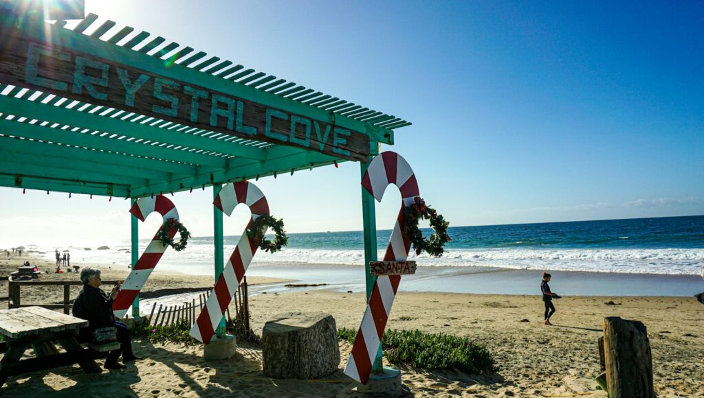 A person walks by a pergola covered in giant wooden candy canes for a business decorated with a coastal Christmas aesthetic.