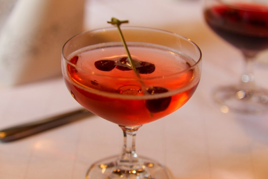 A cranberry prosecco sparkler sits on a white table among other cocktails as part of the Thanksgiving cocktails everyone should consider