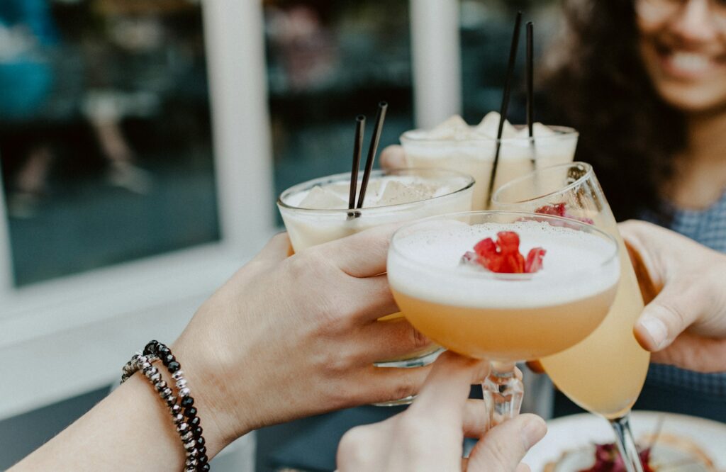 Four ladies cheers their cocktail glasses containing hot buttered rum among other drinks