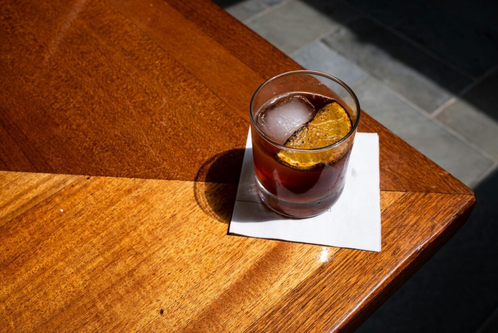 A maple old-fashioned sits on a white napkin on a wooden table