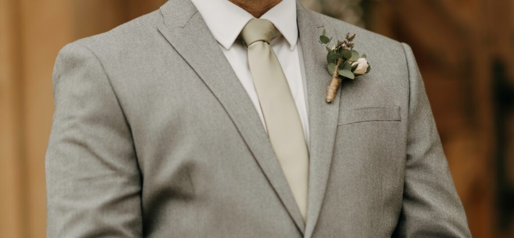 A man wearing a tan suit with a gold tie. 