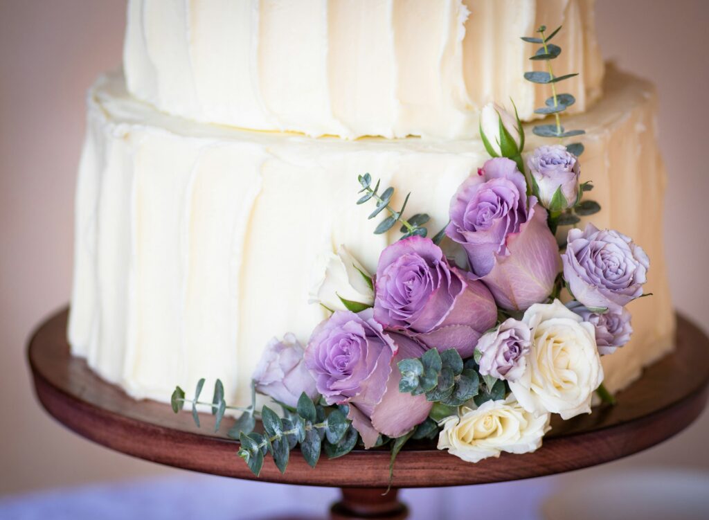 A wedding cake decorated with purple flowers. 