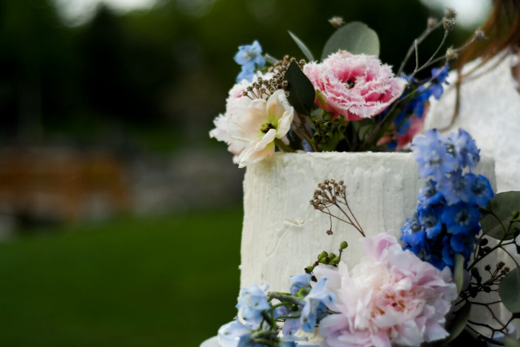 A wedding cake with blue and pink flowers. 