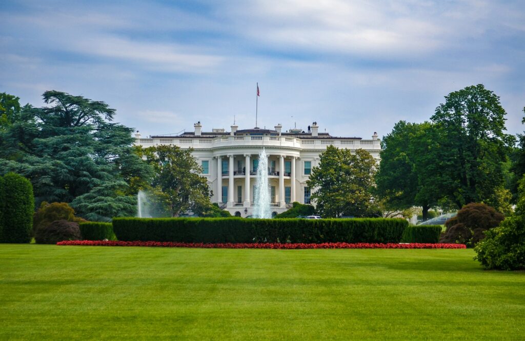 The White House sits under a blue sky on a green lawn. Red flowers line the hedges. It's one of the places to visit on most D.C. travel guides.