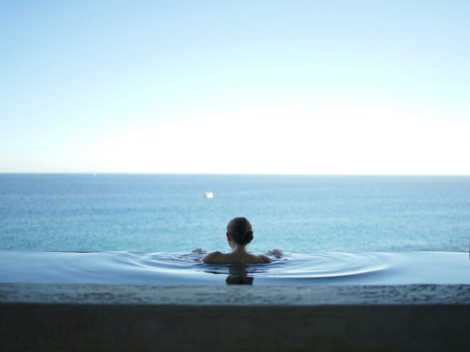 A woman in a pool overlooking the ocean.