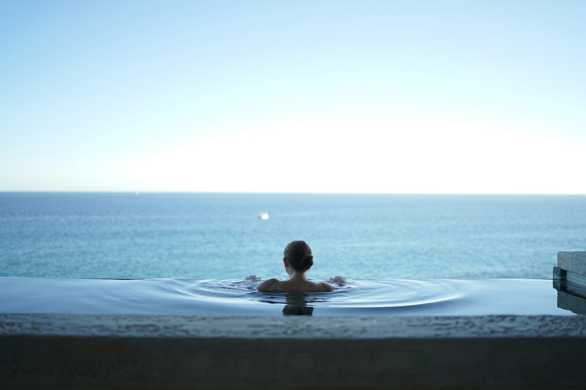 A woman in a pool overlooking the ocean.