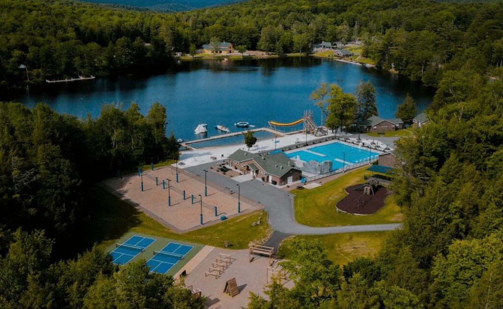 The Camp No Counselors pool, volleyball courts, pickleball courts and lake sit in the middle of a tree-filled valley, the perfect place for an adult summer camp.
