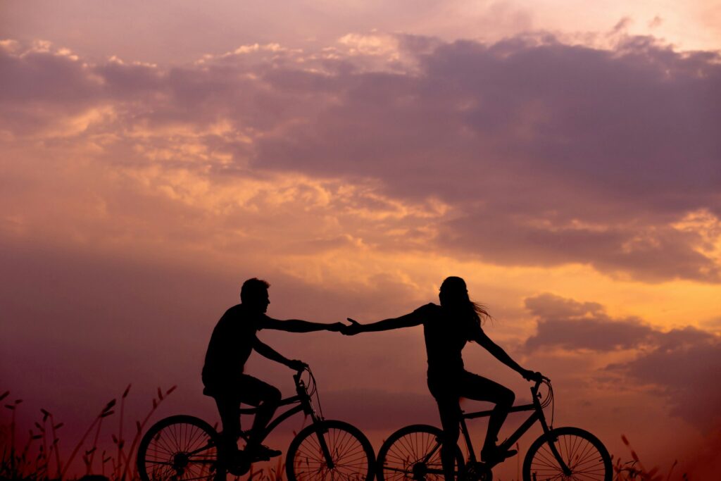 A couple riding bikes at sunset.