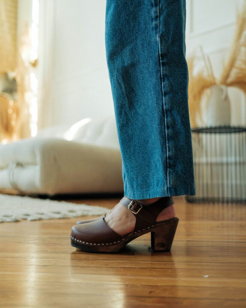 A person wearing shoes and jeans standing in a living room