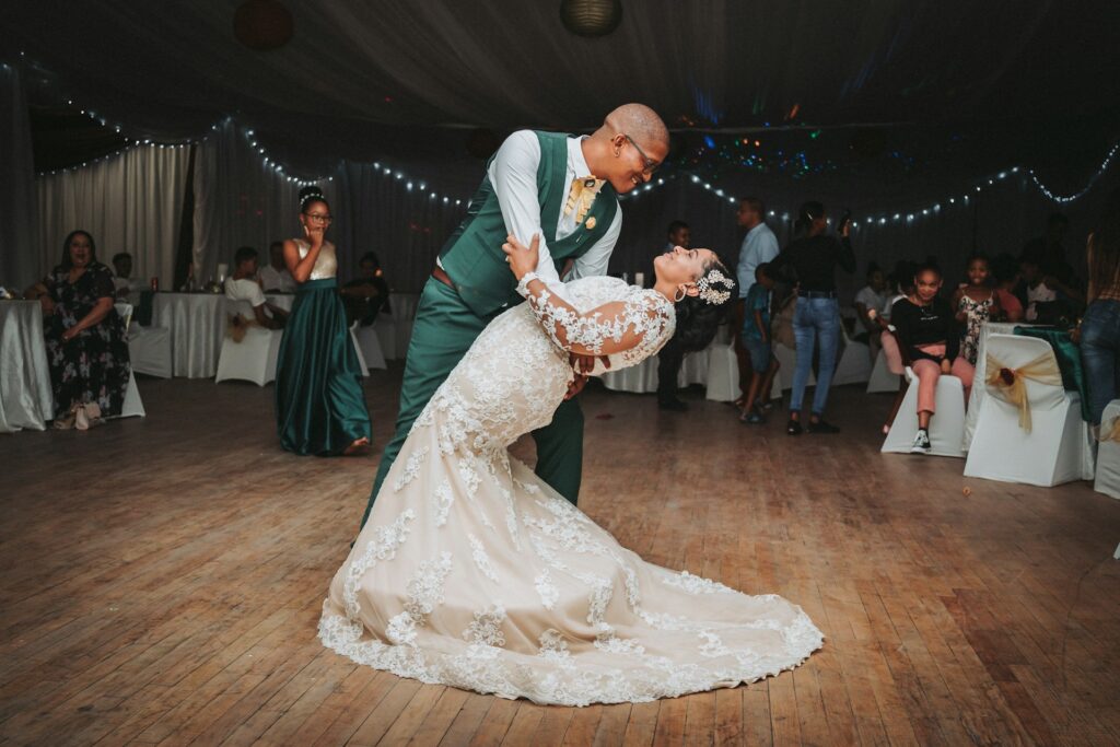 A bride and groom enjoy a solo dance on a wooden floor at their wedding reception.