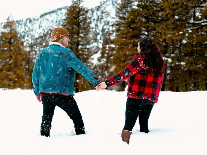 Man and woman holding hands, smiling in the snow