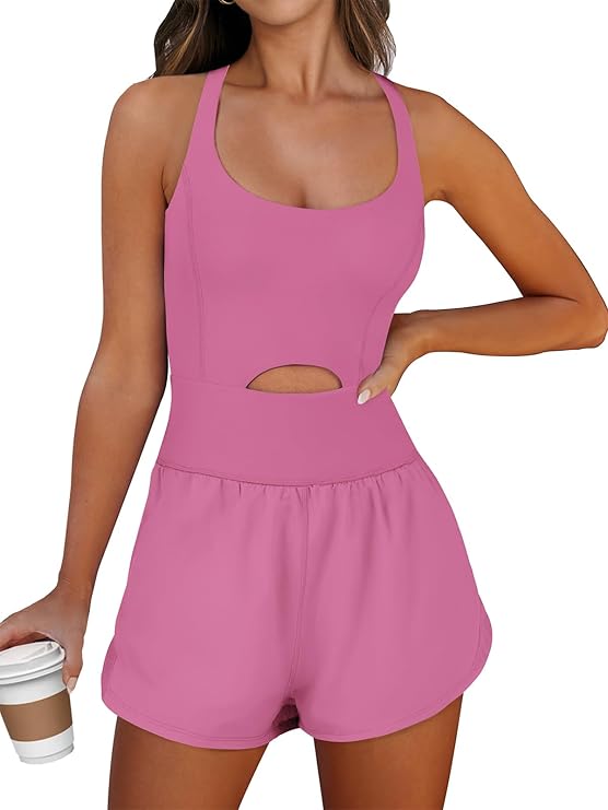 A woman stands against a white background wearing a pink sleeveless romper that fits the pink princess Pilates aesthetic. She holds a white and brown coffee cup.